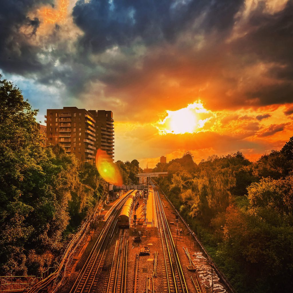 A tube stopping at North Acton station at sunrise