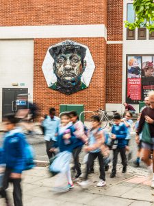 A mural in Shepherd's Bush with a group of school children playing in front of it