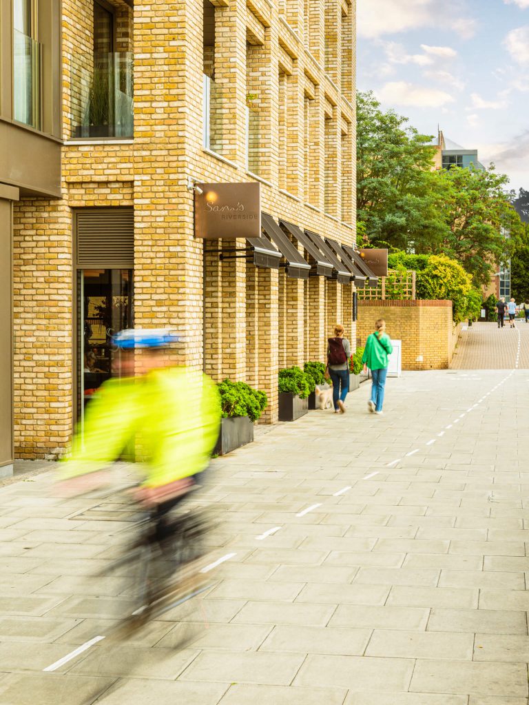 A cyclist blurred in motion travelling along the north bank of the River Thames in Hammersmith