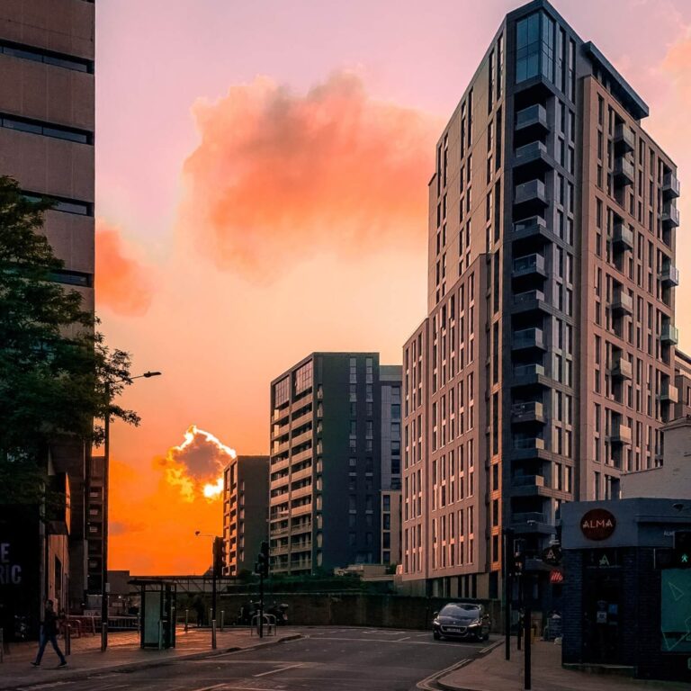 A block of flats in West London with an orange sunset sky in the background