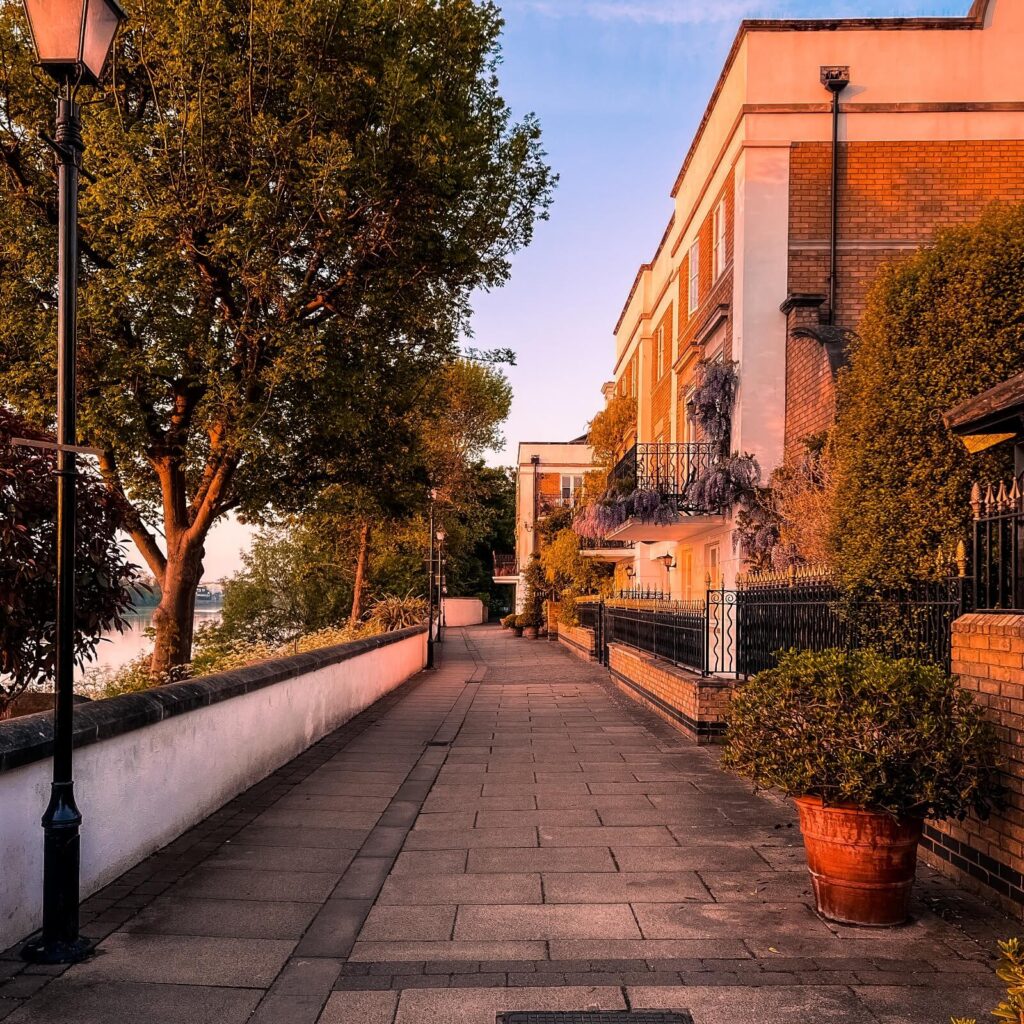 A walkway along the north bank of the River Thames with houses along one edge and a classic London street lamp in the foreground