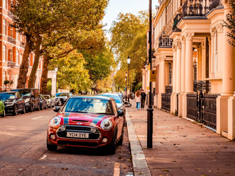 Red Mini Cooper parked on tree-lined road in Kensington