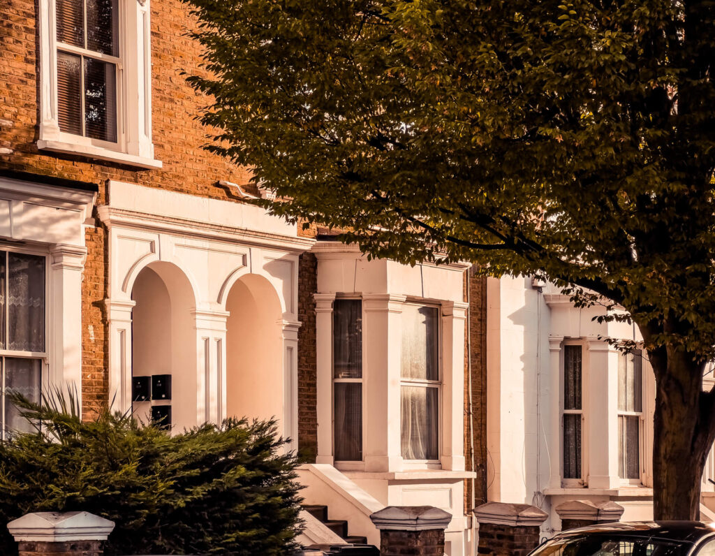 White windows of some orange brick houses in W3 set behind a tree