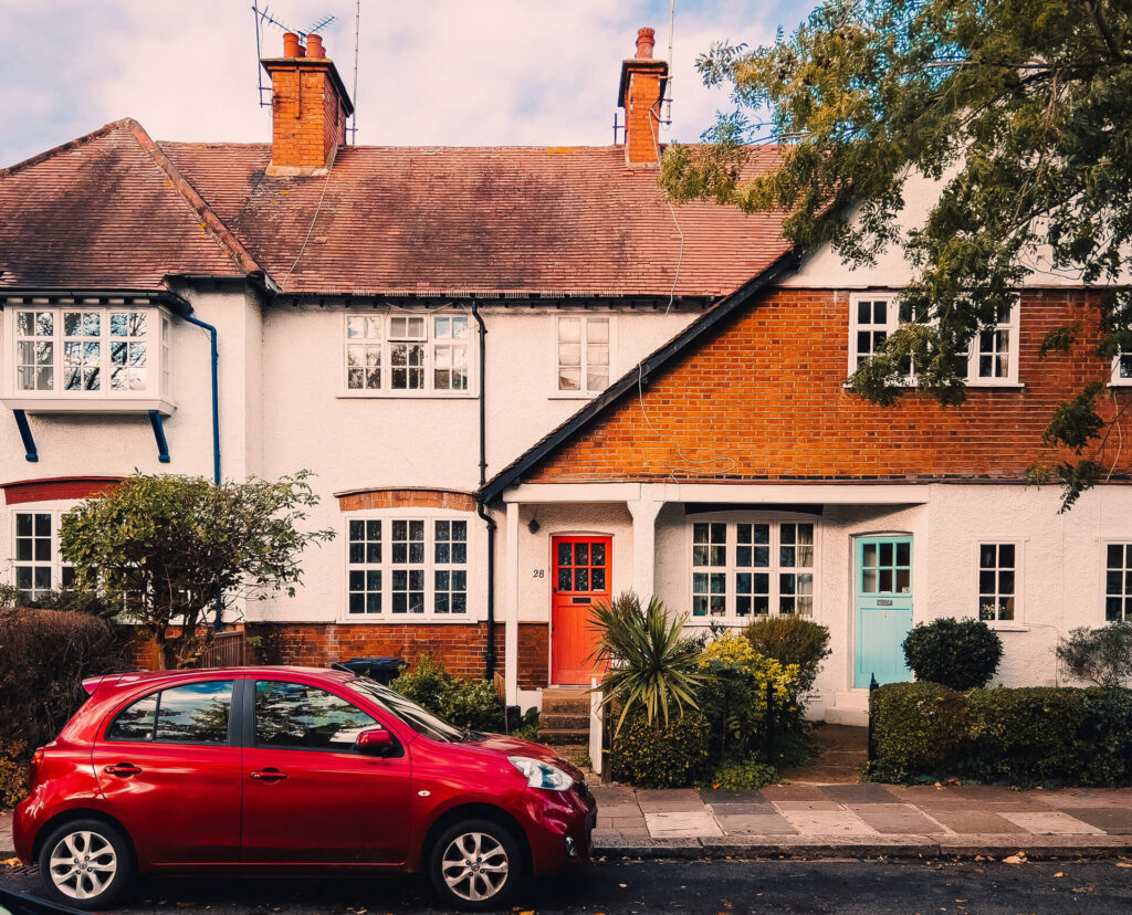 A red Nissan Micra parked outside a typical W5 white and orange coloured house