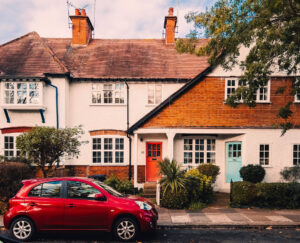 A red Nissan Micra parked outside a typical W5 white and orange coloured house