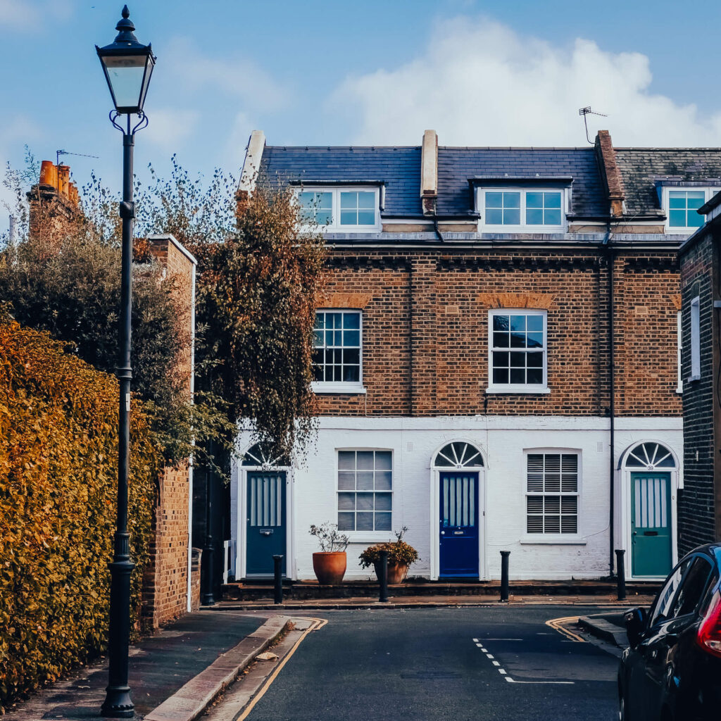 Two houses with blue front doors at the end of a mews in W6