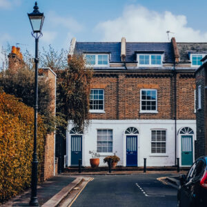 Two houses with blue front doors at the end of a mews in W6