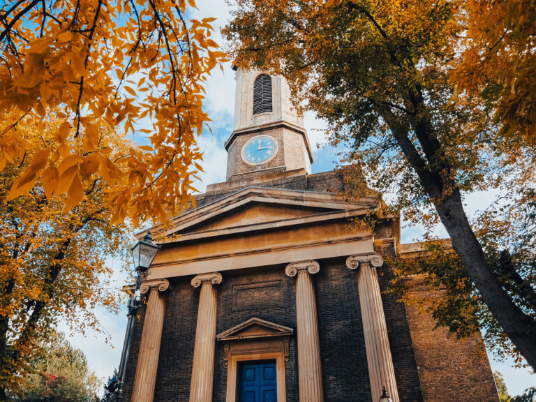 The clocktower of St Peter's Church in Hammersmith set among trees in autumn